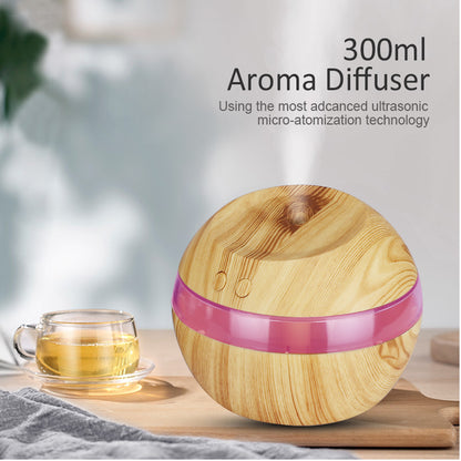 Light woodgrain desktop humidifier with a pink illuminated band beside a cup