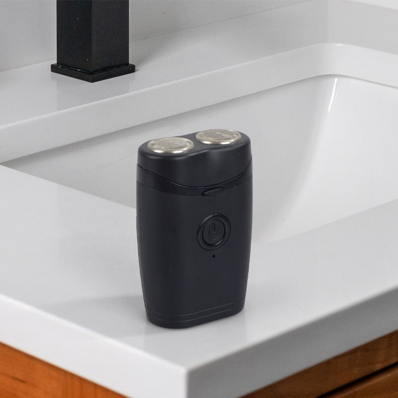 Black dual-head shaver standing beside a bathroom sink